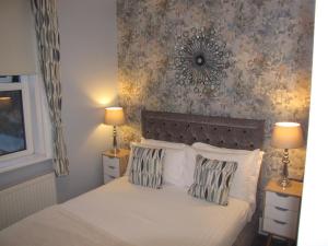 1 dormitorio con 1 cama blanca y 2 almohadas en Ashmira Guest House, en Weymouth