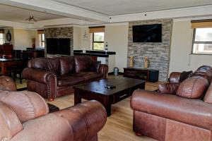 a living room with leather furniture and a fireplace at Palazzo Gardens -Self catering Guesthouse in Swakopmund