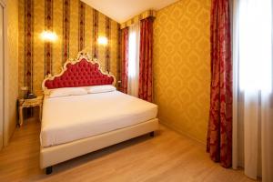a bedroom with a bed with a red headboard at Duomo Boutique Hotel in Chioggia