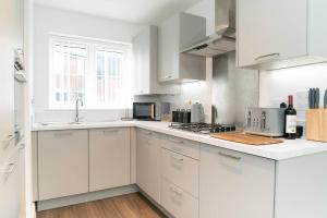 a white kitchen with white cabinets and a sink at Idyllic 3-bed home with Parking in Peterborough by HP Accommodation in Peterborough