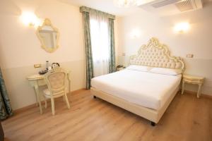 a bedroom with a bed and a table and a mirror at Duomo Boutique Hotel in Chioggia