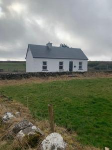 a white house in the middle of a field at Kilmoon Cottage, Entire home in Lisdoonvarna in Lisdoonvarna