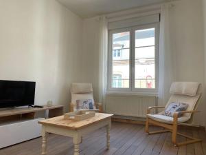 a living room with a tv and a table and chairs at Logement en bord de Meuse « La Jolie Rose » in Haybes