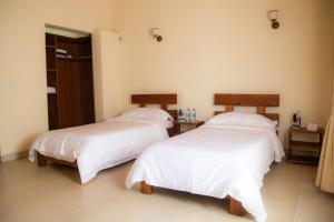 2 camas con sábanas blancas en una habitación en Mahafaly Hotel & Resort, en Antsirabe