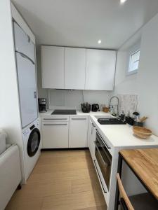 a kitchen with white cabinets and a washer and dryer at Hipster Paris North in Paris