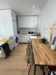 uma cozinha com armários brancos e uma mesa num quarto em Hipster Paris North em Paris
