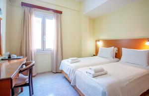 a bedroom with two beds and a desk and a window at Lucia Hotel in Chania Town