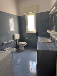 a bathroom with two sinks and a toilet and a window at Villa Paola by the sea in Cozze