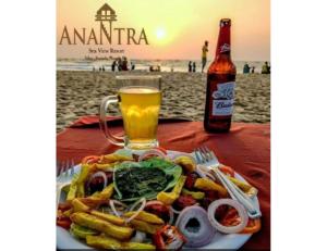 a plate of food on a table with a beer at Anantra Sea View Resort, Agonda, Goa in Agonda