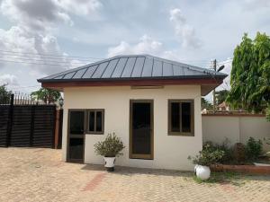 a small house with a black roof at Naturally green and eco friendly 4 bedroom ensuite(Badoo' Parliament) in East Legon