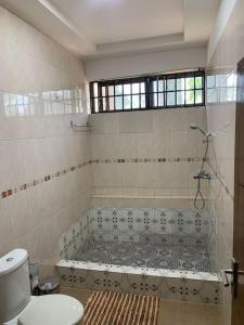 een badkamer met een bad en een toilet bij Naturally green and eco friendly 4 bedroom ensuite(Badoo' Parliament) in Oost-Legon