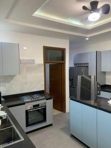 a kitchen with a stove and a ceiling fan at Naturally green and eco friendly 4 bedroom ensuite(Badoo' Parliament) in East Legon