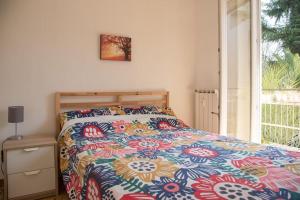 a bedroom with a bed with a colorful comforter and a window at Gibilmanna Home in Rome