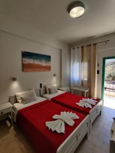 two beds in a bedroom with red sheets and white pillows at Dimitris Villa Hotel in Matala +37 photos