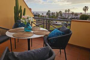 a table with chairs and a vase of flowers on a balcony at Sea view el veril in Adeje