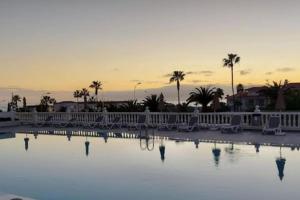 a pool with chairs and palm trees at sunset at Sea view el veril in Adeje