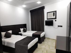 een hotelkamer met 2 bedden en een televisie bij Batw باتوا لشقق المخدومة in Al Baha