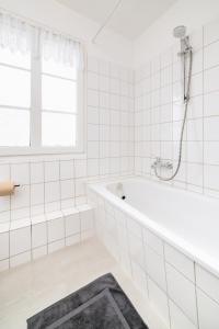 a white tiled bathroom with a tub and a window at Perfect for 6 guests Kitchen Parking Netflix in Wuppertal