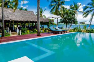 a swimming pool at a resort with a view of the ocean at Long Beach Resort, Nosy Be in Nosy Be