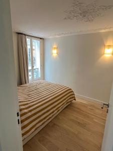 1 dormitorio con cama de rayas y ventana en Appartement d'architecte au cœur de Paris 9, en París