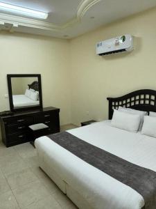 a bedroom with a bed and a dresser with a mirror at قصر نوماس للشقق المخدومة الواديين in Al Wadeen