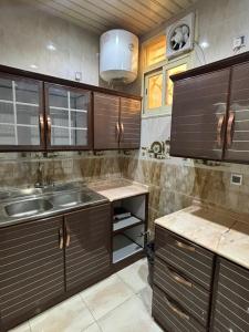 a kitchen with wooden cabinets and a sink at قصر نوماس للشقق المخدومة الواديين in Al Wadeen