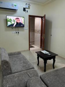 a living room with a couch and a tv on the wall at قصر نوماس للشقق المخدومة الواديين in Al Wadeen