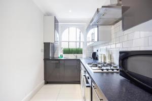 a kitchen with a black counter top and a stove at Larger Groups Canary Wharf Apartment with Large Garden & Parking in London