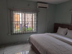 Schlafzimmer mit einem Bett und einem Fenster in der Unterkunft Biddex Lodge & Hotels in Benin-Stadt