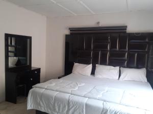 Schlafzimmer mit einem großen Bett mit einem schwarzen Kopfteil in der Unterkunft Biddex Lodge & Hotels in Benin-Stadt