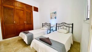 Cet hébergement comprend 2 lits dans une chambre dotée de murs blancs et de placards en bois. dans l'établissement Piso en el centro del Puerto De la Cruz, à Puerto de la Cruz