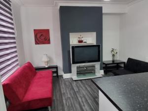 a living room with a red couch and a flat screen tv at Be our Guest! Stylish-Free parking-Central location in Headingley