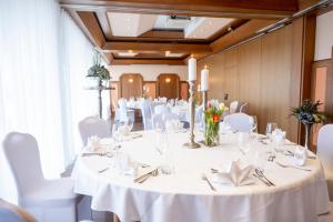 a room with a white table with white chairs and a room with a table set at Hotel Berghof in Petersberg