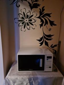 un microondas sentado en una mesa con una flor en la pared en Garsoniera MAIA Slănic-Moldova, en Slănic-Moldova
