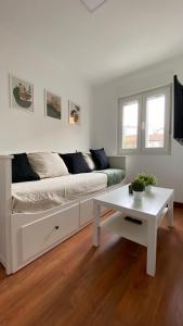 Sala de estar blanca con sofá y mesa en Apartamento cerca de centro y playa, en Santander