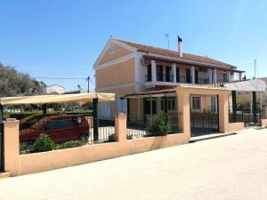 a house with a fence and a car in front of it at Nikos Apartments 2 in Kavos