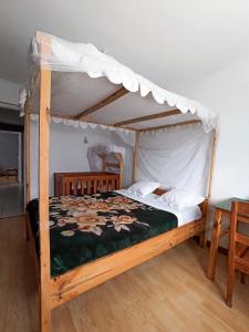 a bedroom with a wooden bed with a canopy at Chez Jeanne Chambre d'Hôte in Antananarivo