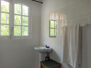 a white bathroom with a sink and a window at Chez Jeanne Chambre d'Hôte in Antananarivo