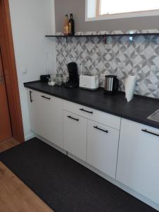 a kitchen with white cabinets and a black counter top at Land.Natur.Erholen. in Wolgast
