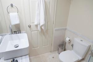 a white bathroom with a toilet and a sink at Skyline Parorama in Mathía +21 photos
