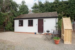 a small white tiny house with a wooden door at Pass the Keys The White House Holiday Cottage in Highley