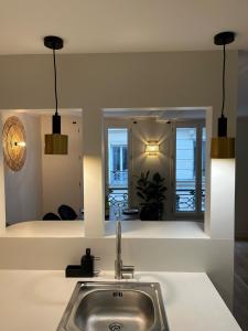 een keuken met een wastafel en een spiegel bij Appartement d'architecte au cœur de Paris 9 in Parijs