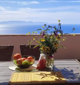 a table with a bowl of fruit and a vase of flowers at Skyline Parorama in Mathía