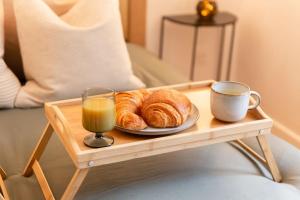a tray with a plate of croissants and a cup of orange juice at Love Life Room-Jacuzzi-Netflix-Accès-24/7-Privé in Étampes