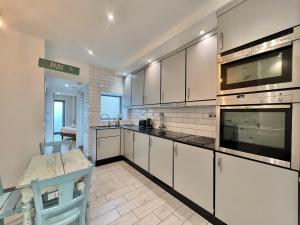 eine Küche mit weißen Schränken und einem Tisch darin in der Unterkunft Seymour Place Lovely contemporary ground floor apartment in Dean + 8 Fotos