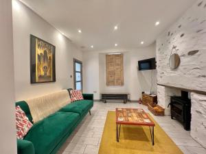 a living room with a green couch and a fireplace at Lovely contemporary ground floor apartment. in Dean