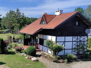 a cottage with a red roof and white windows at Dabki Village in Dąbki