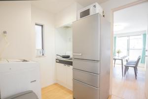 a white kitchen with a refrigerator and a table at Comfort Walk to Takadanobaba Sta. - 3LDK SoYi / Dual Bathrooms & Washrooms for Families & Groups in Tokyo