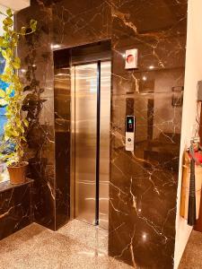 a stainless steel elevator in a bathroom with a marble wall at Gamla INN, Munnar in Munnar