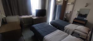 a hotel room with two beds and a television at El Greco in Patra